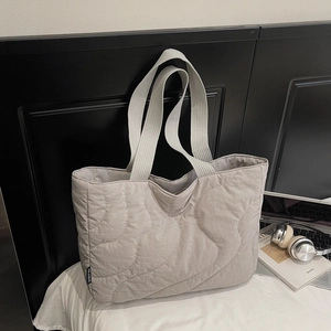 Detail of light grey quilted tote bag with wave stitching and wide ribbon handles