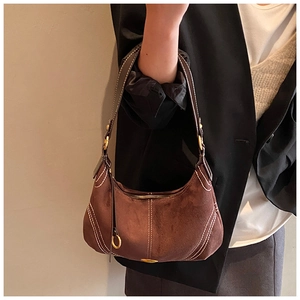 Detailed view of dark brown suede shoulder bag featuring contrast white stitching and gold hardware