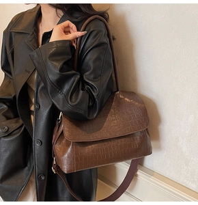Detail view of dark brown croc-embossed leather tote with stylish wide fabric strap