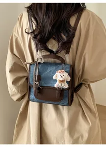 Detail of blue denim backpack with brown leather strap and cute puppy pendant on a model