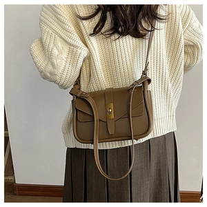 Dettaglio di una borsa a tracolla marrone minimalista con chiusura a scatto dorata