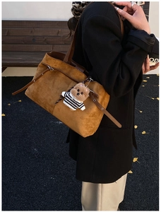 Détail du sac cabas en daim marron avec bandoulière en cuir et charm ours en extérieur