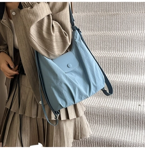 Detail of blue quilted tote bag with magnetic snap closure and adjustable shoulder strap
