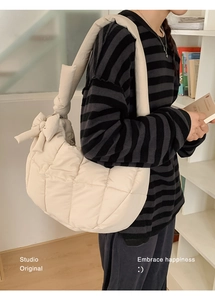 Détail du sac hobo matelassé beige avec grand nœud décoratif sur la bandoulière