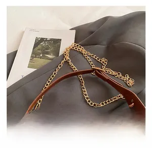 Détail du sac en cuir marron avec chaîne dorée et finitions de couture précises