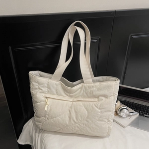 Detail of quilted tote bag in off-white fabric with large wavy stitching and zipped pocket