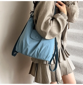 Detail of light blue nylon tote bag with wide strap on shoulder of a female model