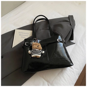 Détail du sac fourre-tout noir en similicuir brillant avec boucle et ours en peluche