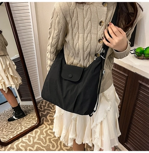 Close-up of black nylon tote bag with flap closure and adjustable shoulder strap