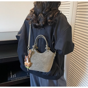 Detail of olive grey frosted leather handbag with knotted handle and cute bear charm