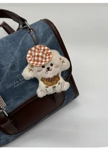 Plush puppy bag charm with orange checkered hat on denim backpack detail view