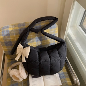 Détail du sac matelassé noir avec un grand nœud beige et une bandoulière avec nœuds doux