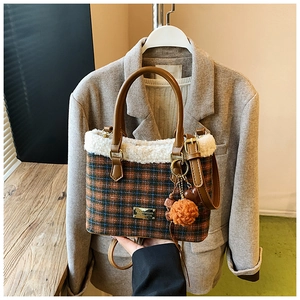 Detail der karierten Winter-Eimertasche mit Lammfellbesatz und Plüsch-Pompon-Anhänger