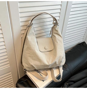 Detail view of cream white tote bag with wrinkled texture and adjustable shoulder strap