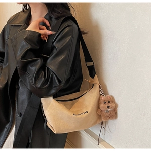 Detail of suede tote bag with black strap and brown teddy bear charm for women