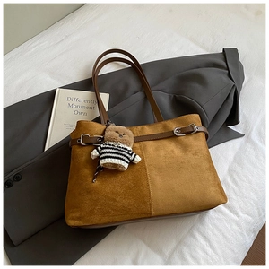 Détail du sac cabas en suède avec bandoulière en cuir et accessoire charm d'ours mignon