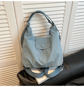 Detail of the light blue-grey nylon tote bag with magnetic flap and soft pleated texture