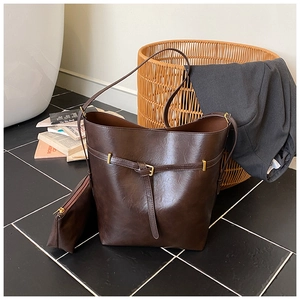 Detail view of dark brown bucket bag set with inner zipper pouch on tiled floor