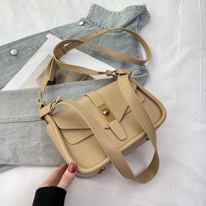 Dettaglio borsa a tracolla in pelle beige con chiusura girevole dorata e tracolla regolabile