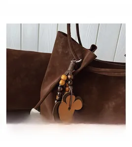 Close-up of brown suede bucket bag featuring floral charms and wooden bead tassels