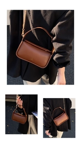 Détail du sac en cuir marron avec bandoulière chaîne dorée et logo métallique