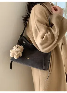 Détail du cabas en daim café avec surpiqûres blanches et pendentif ours en peluche doux