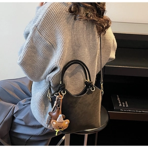 Detailed view of black bucket bag with contrast stitching and cute bear charm pendant