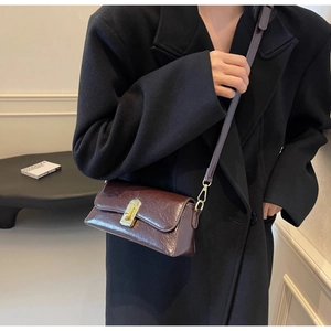 Détail du sac à main bordeaux avec fermoir doré et fine bandoulière en cuir souple