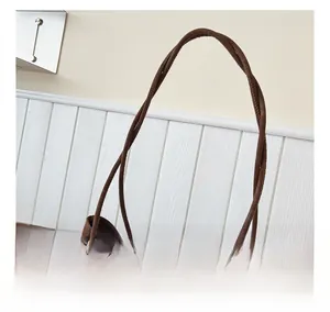 Detail of round coffee suede handles and wooden bead charm on a spacious tote bag