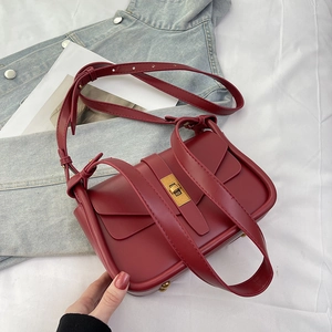 Dettaglio borsa a tracolla bordeaux con chiusura girevole dorata e nodo decorativo in pelle
