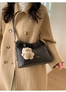 Détail du sac fourre-tout en daim noir avec surpiqûres et charmant petit ours en peluche brun