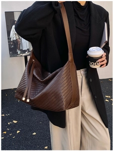 Vue détaillée du sac hobo tressé marron foncé avec pompon porté par le modèle