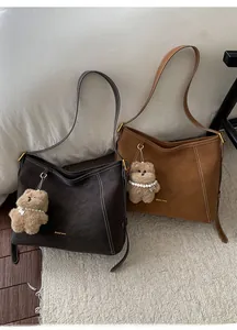 Détail de sacs cabas en daim marron et camel avec surpiqûres et pendentif ours en peluche