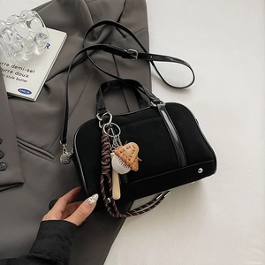 Dettaglio borsa bowling in camoscio nero con ciondolo da baseball e finiture in metallo argento