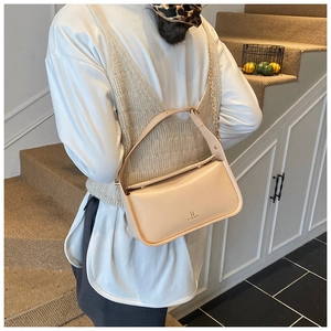 Sac bandoulière minimaliste en cuir beige porté par un mannequin en tenue décontractée