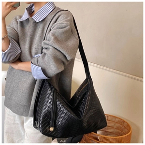 Sac hobo chic tressé noir porté par un mannequin avec un pull gris et des rayures bleues