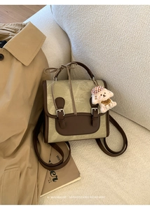 Detail of vintage khaki backpack with brown leather straps and cute puppy pendant