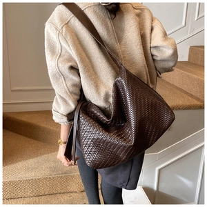 Détail d'un sac hobo tressé marron foncé avec motif damier porté par un mannequin