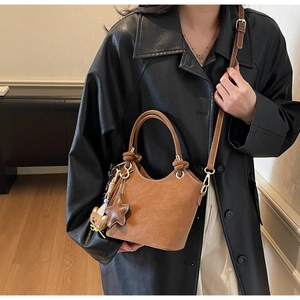 Brown bucket bag with cute bear charm worn by a model in a black coat for office