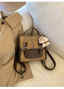 Detail view of a vintage faux leather backpack with checkered ribbon and plush bear charm