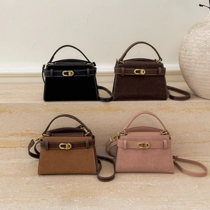 Multiple colors of vintage suede crossbody bags with metal buckles on stone steps