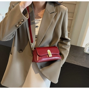Gros plan sur un sac bandoulière rouge brillant avec boucle rotative en métal doré