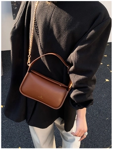 Détail du sac à main en cuir marron avec bandoulière chaîne dorée et logo