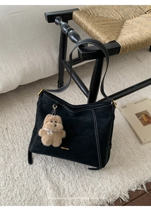 Vue détaillée du sac à bandoulière noir mat avec surpiqûres blanches et charme d'ours