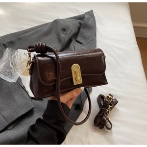 Détail du sac à main en cuir marron foncé avec fermoir doré et bandoulière