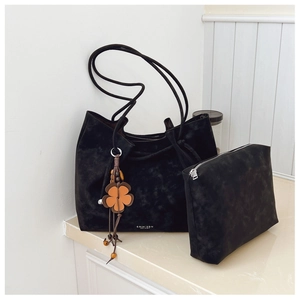 Detail view of the black matte tote bag set with inner pouch and a floral charm pendant