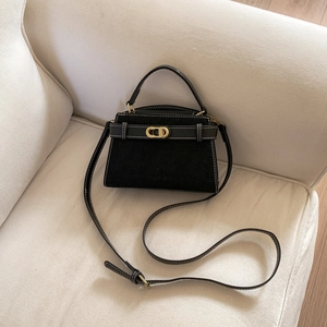 Detail of black suede and leather bag with gold oval twist lock and white contrast stitching