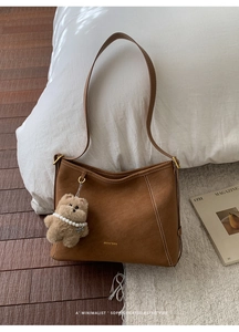 Détail du cabas en daim marron avec charm ours en peluche et logo métallique doré