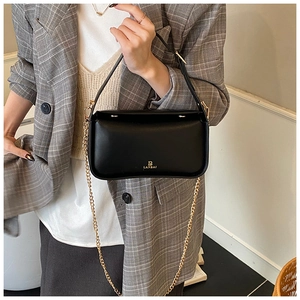 Détail d'un sac bandoulière noir avec logo doré B LANBAI sur un blazer à carreaux