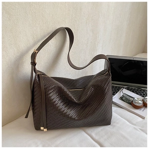 Détail d'un grand sac cabas tressé marron foncé avec une texture riche et des boucles